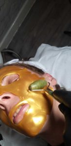 woman in salon with gold face mask on